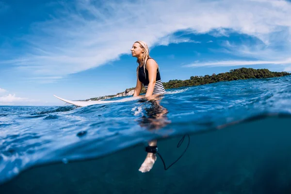 Surfista mulher sentar-se na prancha de surf e esperando onda no mar — Fotografia de Stock