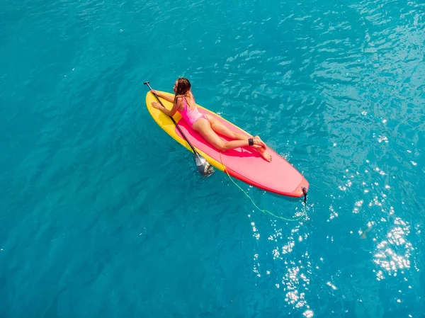 Donna attraente rilassarsi su stand up paddle board in blu oceano. S — Foto Stock