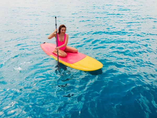 Atractiva mujer en traje de baño flotando en stand up paddle board o — Foto de Stock