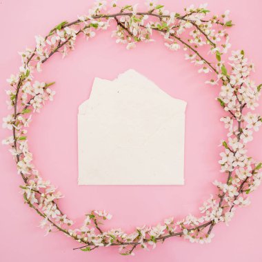 Bahar çiçeklerinden yapılmış yuvarlak çerçeve ve üzerinde kağıt vintage zarf