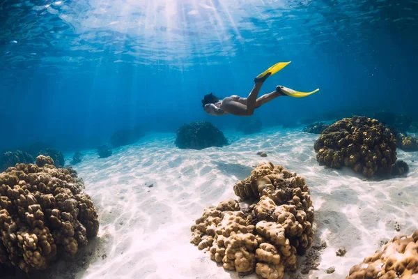 Free diver young girl with yellow fins glides over sandy bottom — Stock Photo, Image