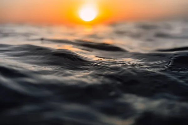 Sunset and waves in ocean. Warmy water texture with bokeh — Stock Photo, Image