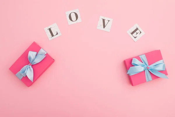 Sevgililer Günü konsepti, aşk sözcüğü ve pembe arka grubunda hediye. — Stok fotoğraf