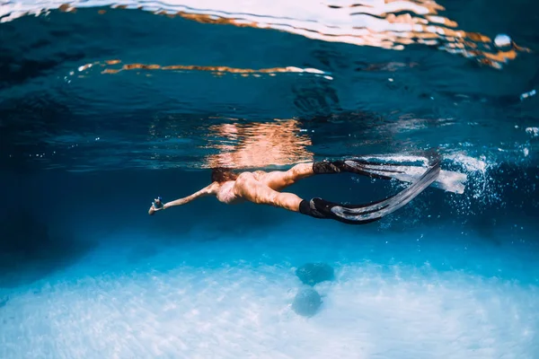 Kobieta freediver z płetwami pływać nad piaszczystym morzem pod wodą — Zdjęcie stockowe