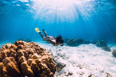 Yüzgeçli özgür kız mavi okyanusta kumlu dipte süzülüyor.