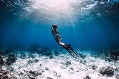Yüzgeçli serbest dalgıç derin mavi okyanusta suyun altında süzülüyor.