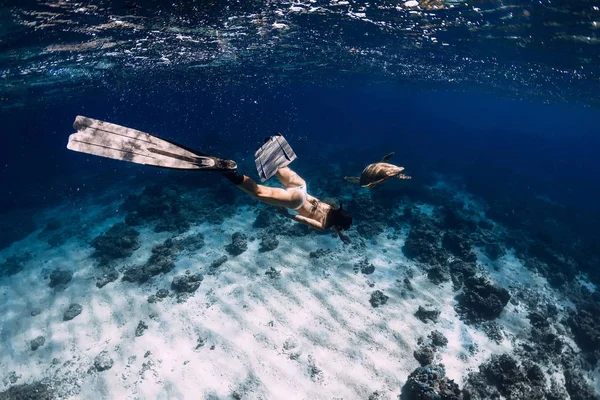 Freediver z płetwami ślizga się pod wodą z żółwiem w oceanie. Piasek — Zdjęcie stockowe