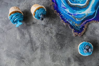 Mavi kremalı yaban mersinli kekler ve gri renkli reçine sanatı.