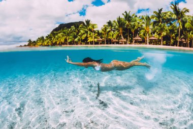 Mauritius 'ta saydam mavi okyanusta yüzen bir kadın.