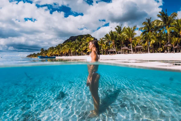 Vrouw poserend in een doorzichtige blauwe oceaan. Zwemmen in blauw water a — Stockfoto