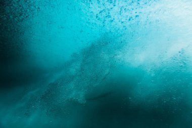 Wave with bubbles underwater. Transparent blue ocean in underwat