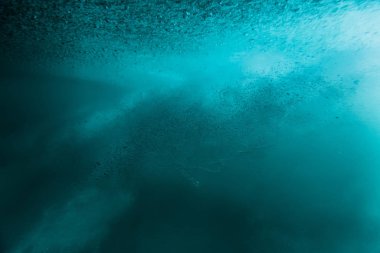 Wave with bubbles underwater. Transparent blue ocean in underwat