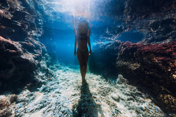 Frau im Bikini posiert unter Wasser nahe Korallen im Ozean. — Stockfoto