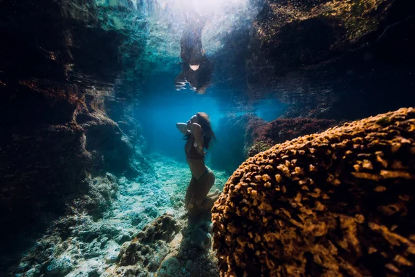 Vrouw in bikini poseren onderwater in de buurt van koralen in oceaan. — Stockfoto