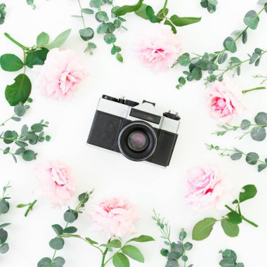 Beyaz arka planda izole edilmiş eski bir kamera ve çiçekler. Düz yatıyordu. Üst görünüm.