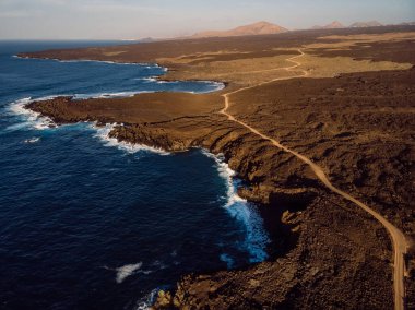 Lav kayalıklarının ve günbatımı tonlarıyla okyanusun havadan görünüşü. Lanzarote, Kanarya Adaları.