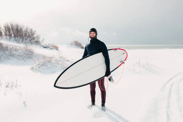 サーフボードと寒い冬と男性サーファー ウェットスーツのサーファーと雪の日 — ストック写真