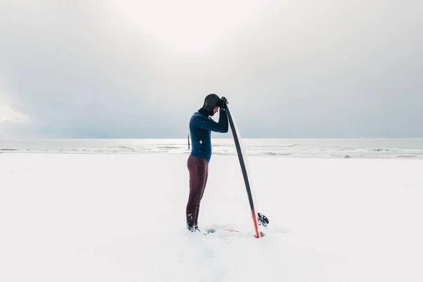 サーフボードと寒い冬と男性サーファー ウェットスーツのサーファーと雪の日 — ストック写真