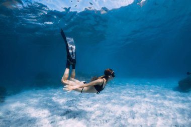 Kadın serbest dalgıç kumlu denizin üzerinde beyaz kumla süzülüyor. Hawaii adasında serbest dalış
