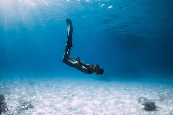 女性のフリーダイバーは 砂の海の底の上にフィンで滑ります 青い海のフリーダイビングと太陽の光 — ストック写真