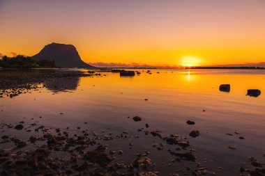 Renkli günbatımında sessiz, cam gibi okyanus. Mauritius 'taki Le Morn Dağı.