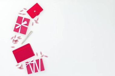 Kırmızı defter, hediye kutusu, beyaz arka planda kalem ve klipler. Düz yatıyordu. Kırmızı dekorasyon