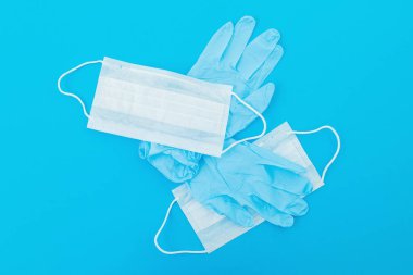 Mavi arka planda virüs ve bakterilerden korunmak için tıbbi maskeler. Maske ve eldivenli salgın konsepti. Düz yatıyordu. Üst görünüm