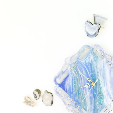 Beyaz zemin üzerinde agat taşları olan reçine sanat saati. Düz yatış, üst görünüm