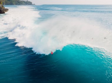 Fıçı dalgalarında sörf yapmanın havadan görüntüsü. Okyanustaki mavi dalgalar ve sörfçüler