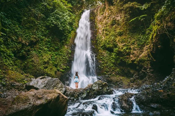 Waterfall in tropical jungle and alone woman. Waterfall in Bali, Indonesia
