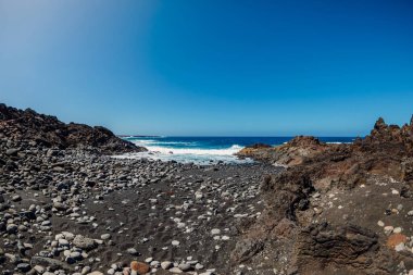 Lanzarote, İspanya 'da siyah volkanik kumlu, taşlı ve okyanuslu plaj.