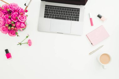 Merkez ofis masası. Dizüstü bilgisayarı, gül buketi, kozmetik ürünleri ve beyaz arka planda günlük olan bir kadın çalışma alanı. Düz yatıyordu. Üst görünüm.