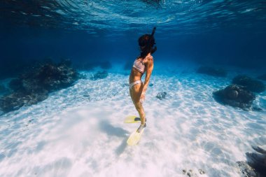 Woman swimming underwater with yellow fins in blue ocean. Freediving or snorkeling in Mauritius clipart