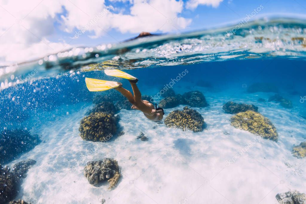 Woman swimming underwater with yellow fins in blue ocean. Freediving or snorkeling in Mauritius