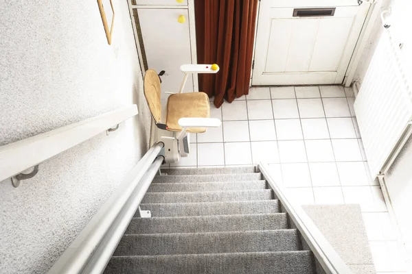 Elevador automático de escadas em escadas levando pessoas idosas e pessoas com deficiência para cima e para baixo em uma casa Imagens Royalty-Free