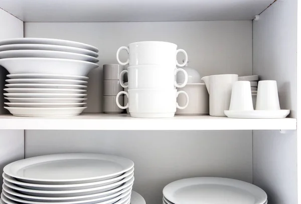 Белый шкаф с белой посудой на кухне, различные чистые блюда — стоковое фото
