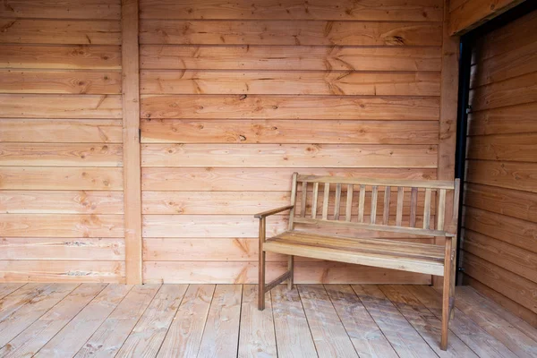 Деревянное сиденье для скамейки на деревянном крыльце, с деревянной крышей крупным планом — стоковое фото
