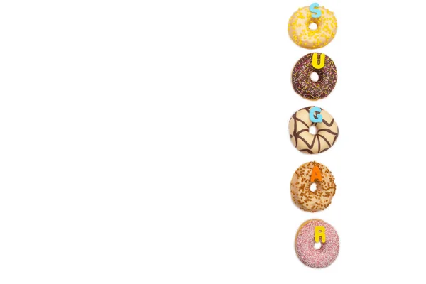 Различные цвета вкусные пончики на белом фоне со словом сахар, пространство для текста — стоковое фото