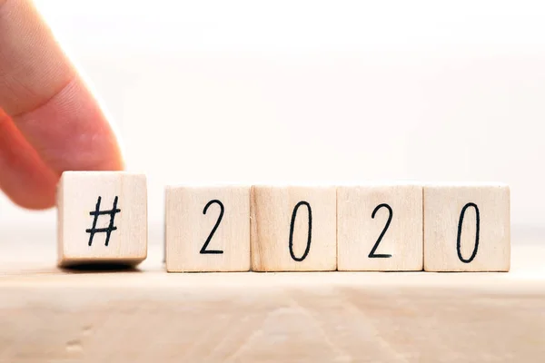 Hashtag 2020 concept, hand change wooden cubes close-up with white background