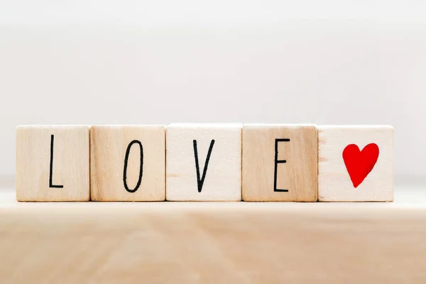 Aşk kelimesi tahta küplerde kırmızı kalpli, beyaz arka planda yakın plan — Stok fotoğraf