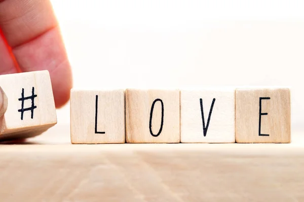 Parola Amore su cubi di legno con hashtag, primo piano vicino sfondo bianco — Foto Stock
