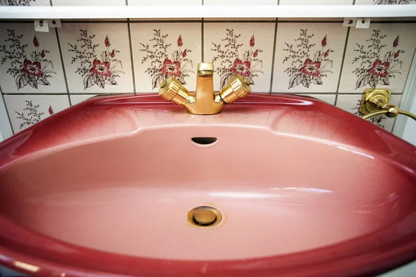 Vintage lavabo rosa con grifo de oro y patrón de flores de azulejos de la pared en el baño —  Fotos de Stock