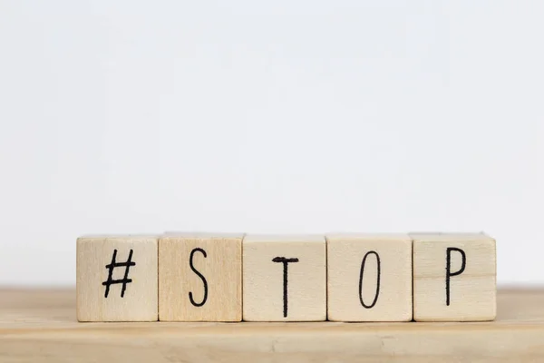 Holzwürfel mit einem Hashtag und dem Wort Stop vor weißem Hintergrund, Social-Media-Konzept — Stockfoto