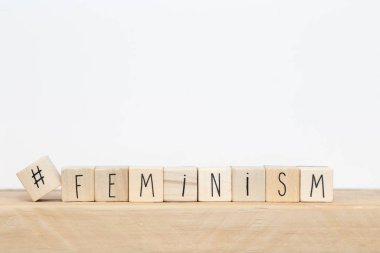 Üzerinde hashtag olan tahta küpler ve beyaz arkaplan yakınlarındaki feminizm, sosyal medya kavramı