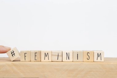 Üzerinde hashtag olan tahta küpler ve beyaz arkaplan yakınlarındaki feminizm, sosyal medya kavramı