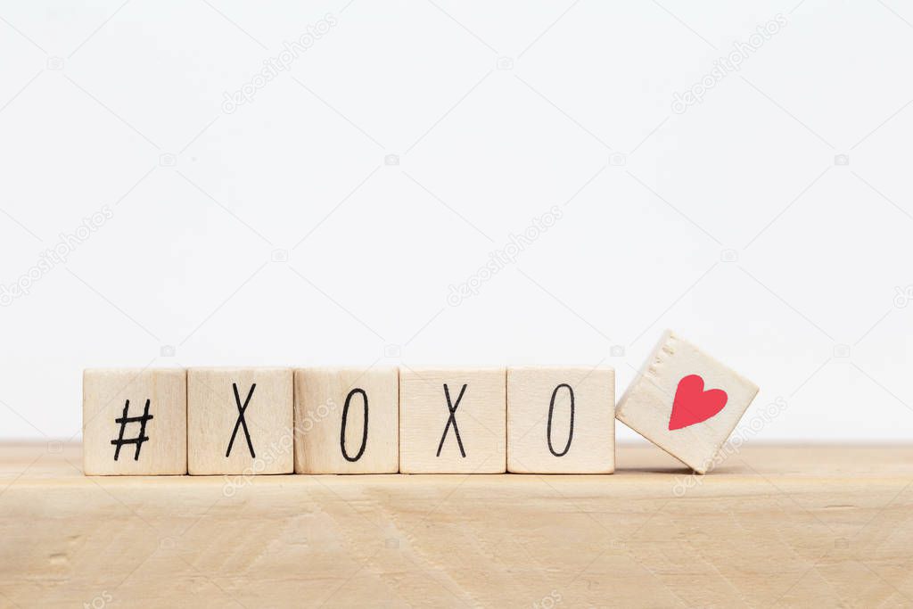 Wooden cubes with hashtag and XOXO hugs and kisses letters of love near white background, social media concept
