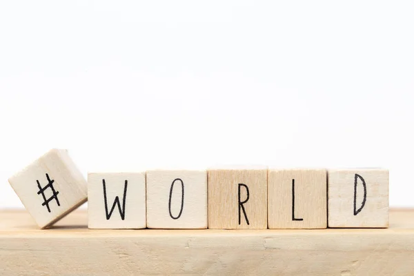 Cubos de madera con un hashtag y la palabra Mundo, concepto de redes sociales cerca de fondo blanco — Foto de Stock