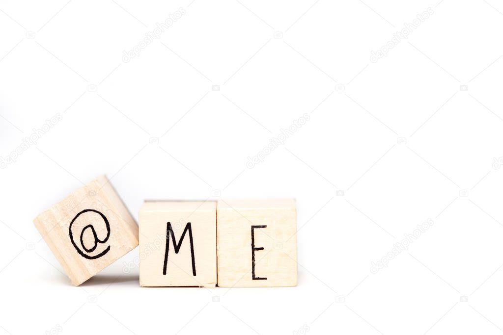 Wooden cube with a commercial At Sign symbol and the word Me isolated on white background, space for text