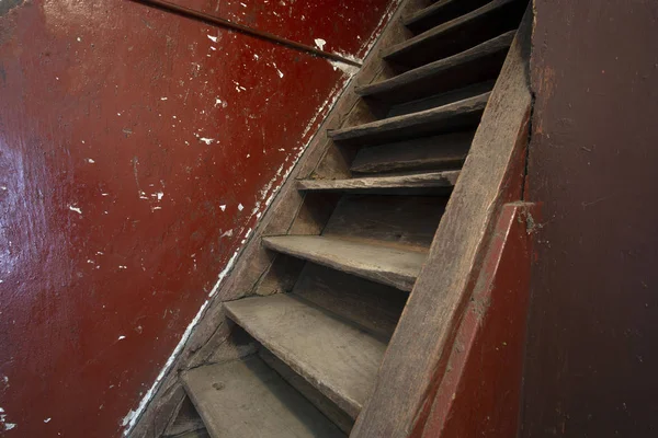 Old damaged brown wooden stairs and red wall leading to the attic, needs renovation — 스톡 사진