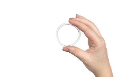 Bir kadının elindeki doğum kontrol yüzüğü beyaz arka planda izole edilmiş, vajinal halka doğum kontrol için kullanılıyor.